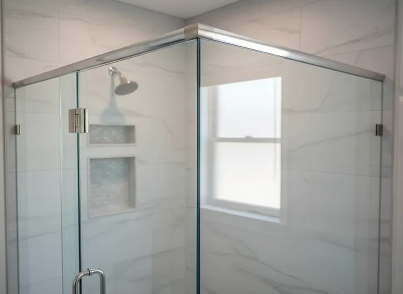 Close-up detail shot of semi-frameless shower door hardware and frame junction, showing minimal aluminum U-channel framing...